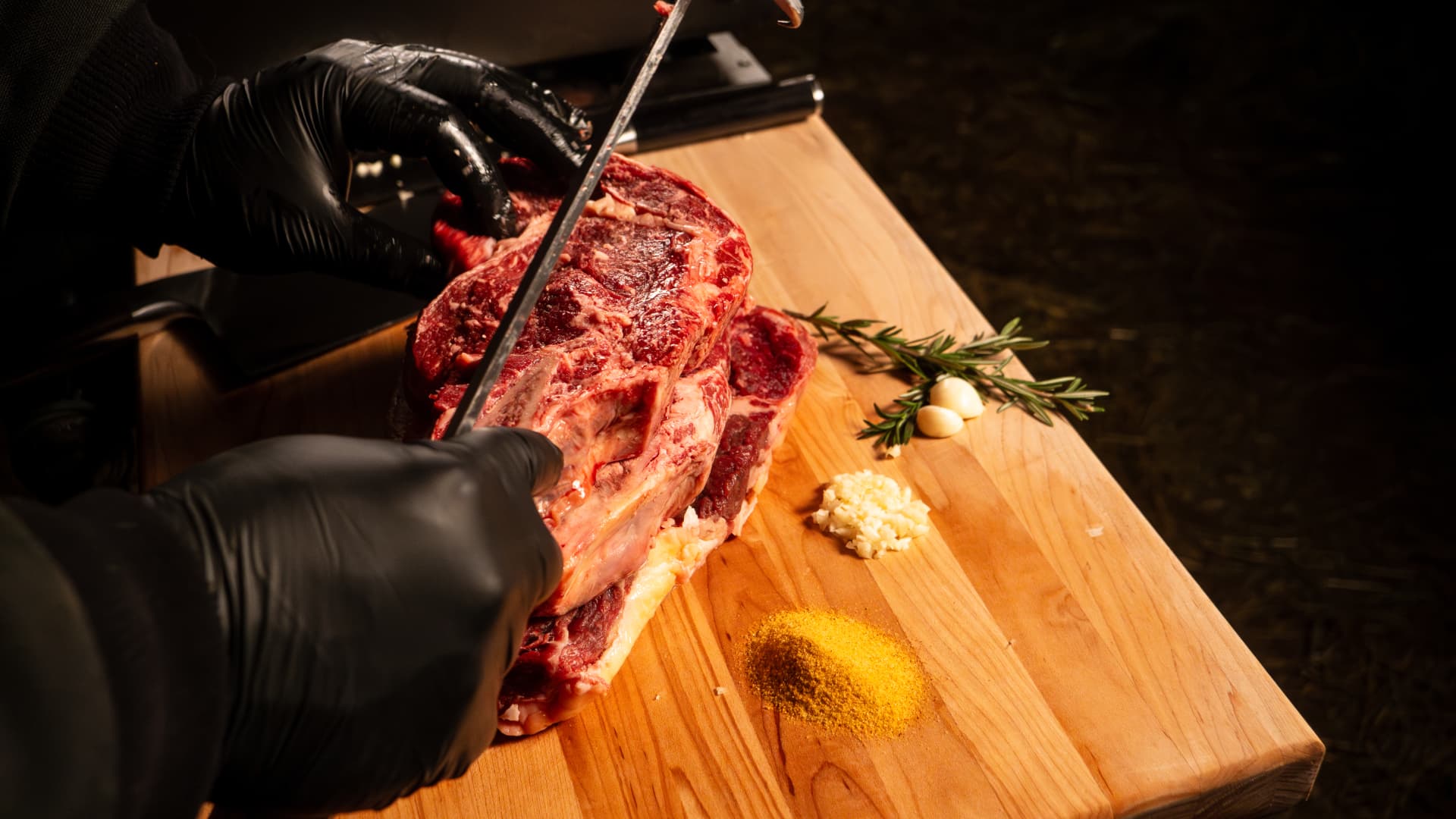 Slicing bone-in steaks from a dry-aged rib section